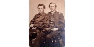 Two men sitting on a chair in front of each other.