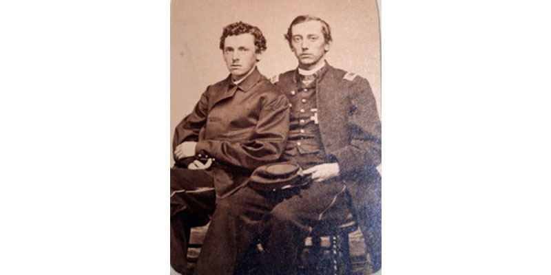 Two men sitting on a chair in front of each other.