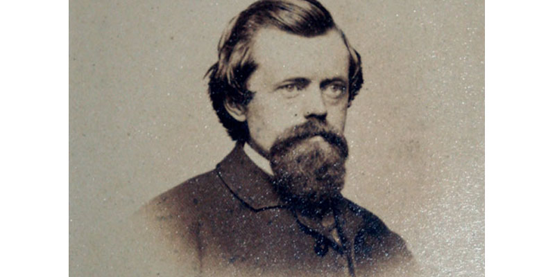 A man with long hair and beard wearing a suit.