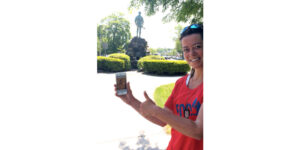 A woman holding up her cell phone in front of a statue.