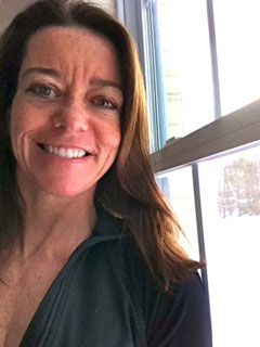 A woman smiling in front of a window.