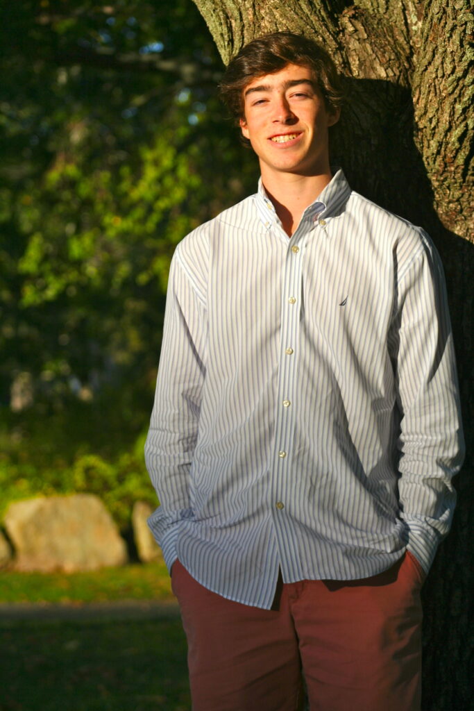 A man standing next to a tree in the sun.