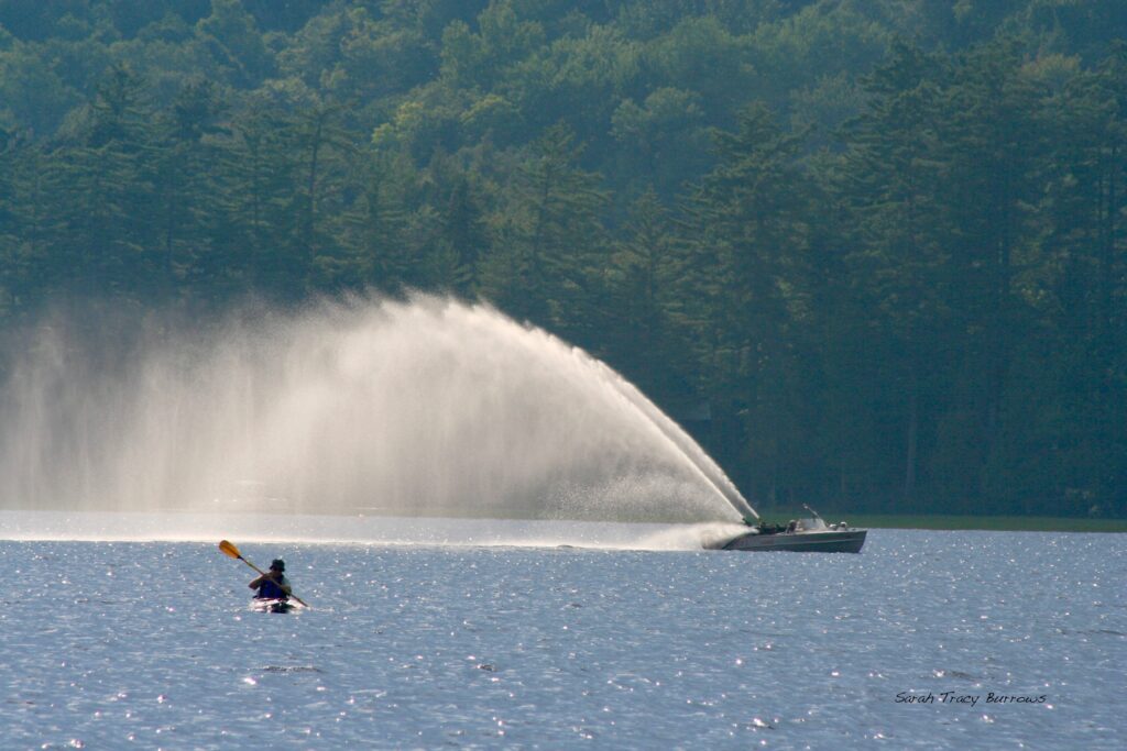 A person in the water with a boat behind him.