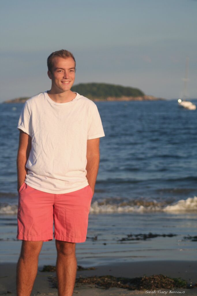 A man standing on the beach in front of water.