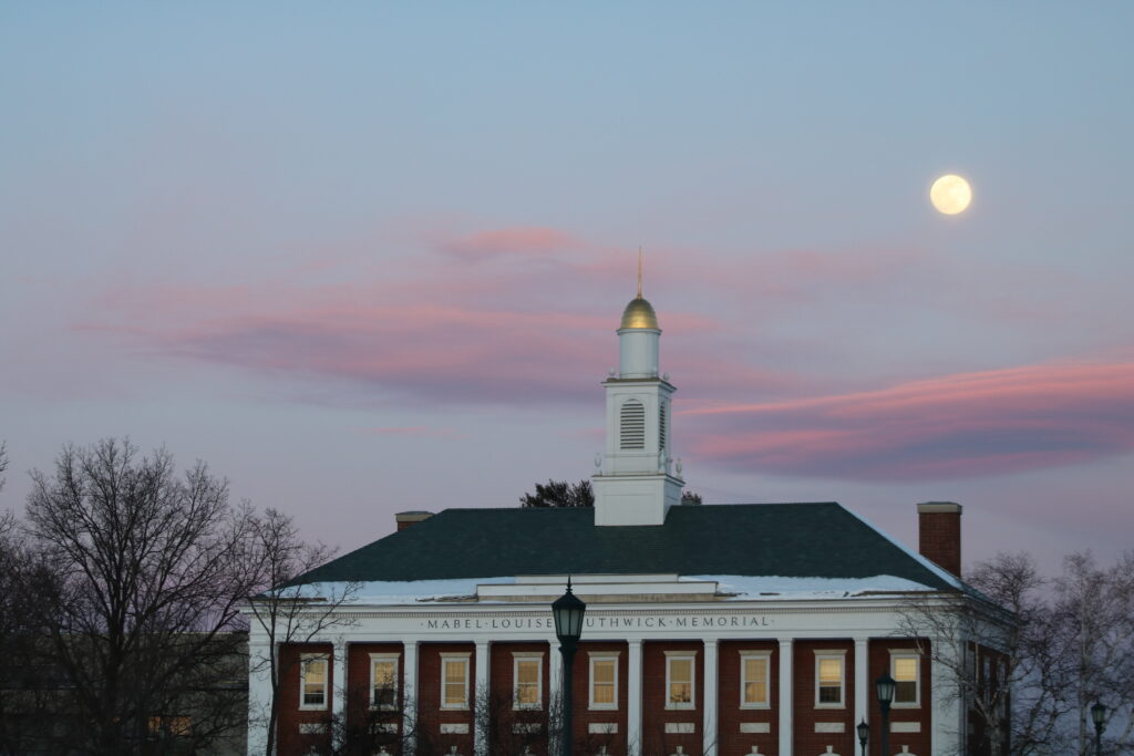 A building with a clock tower and a moon in the background.