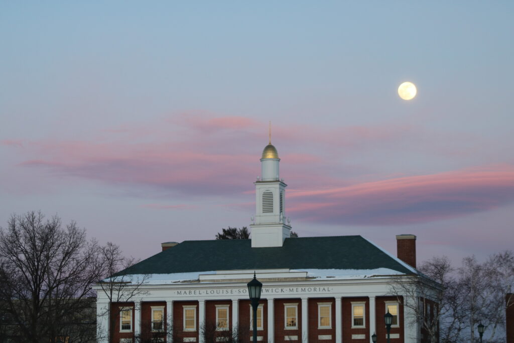 A building with a clock tower and a moon in the background.