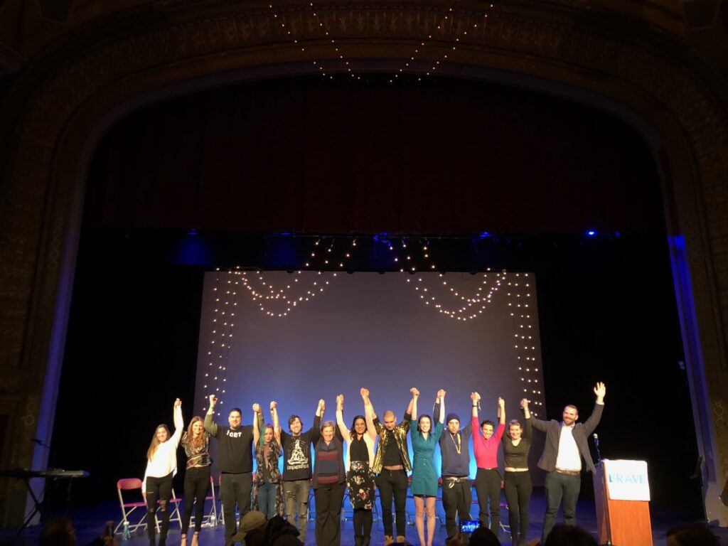 A group of people on stage raising their hands.